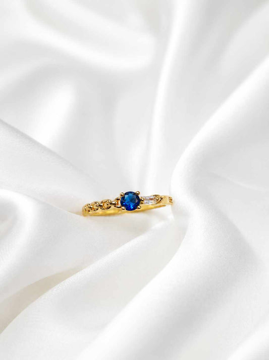 Anillo delgado con una piedra central redonda de color azul profundo