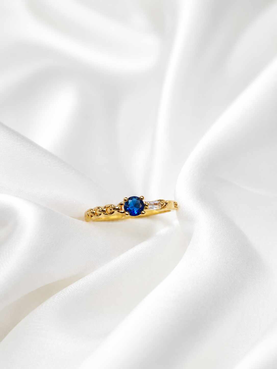 Anillo delgado con una piedra central redonda de color azul profundo
