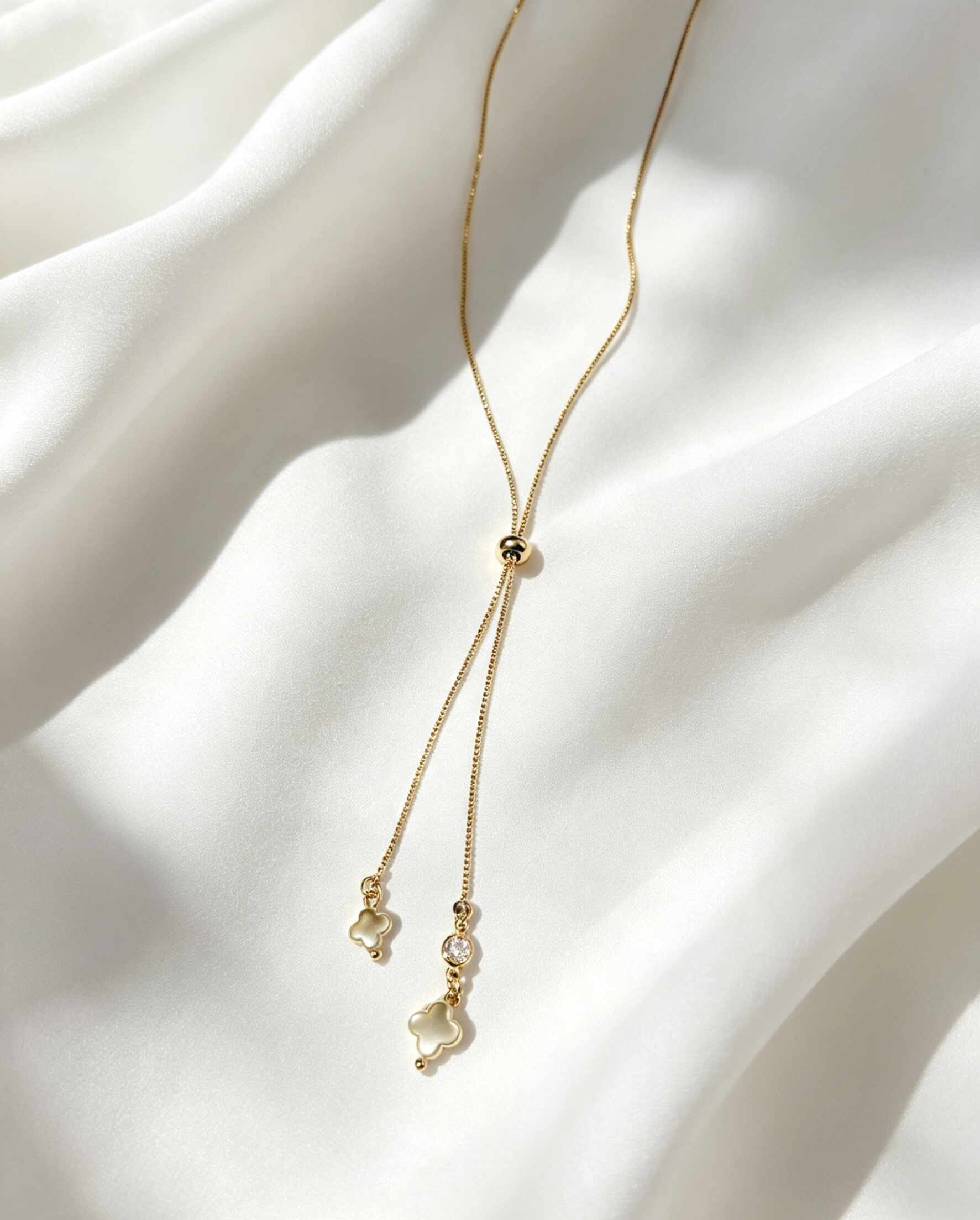 Collar ajustable estilo corbatín, con dijes de trébol de cuatro hojas confeccionados en madre perla y cuenta con un pequeño punto de luz.