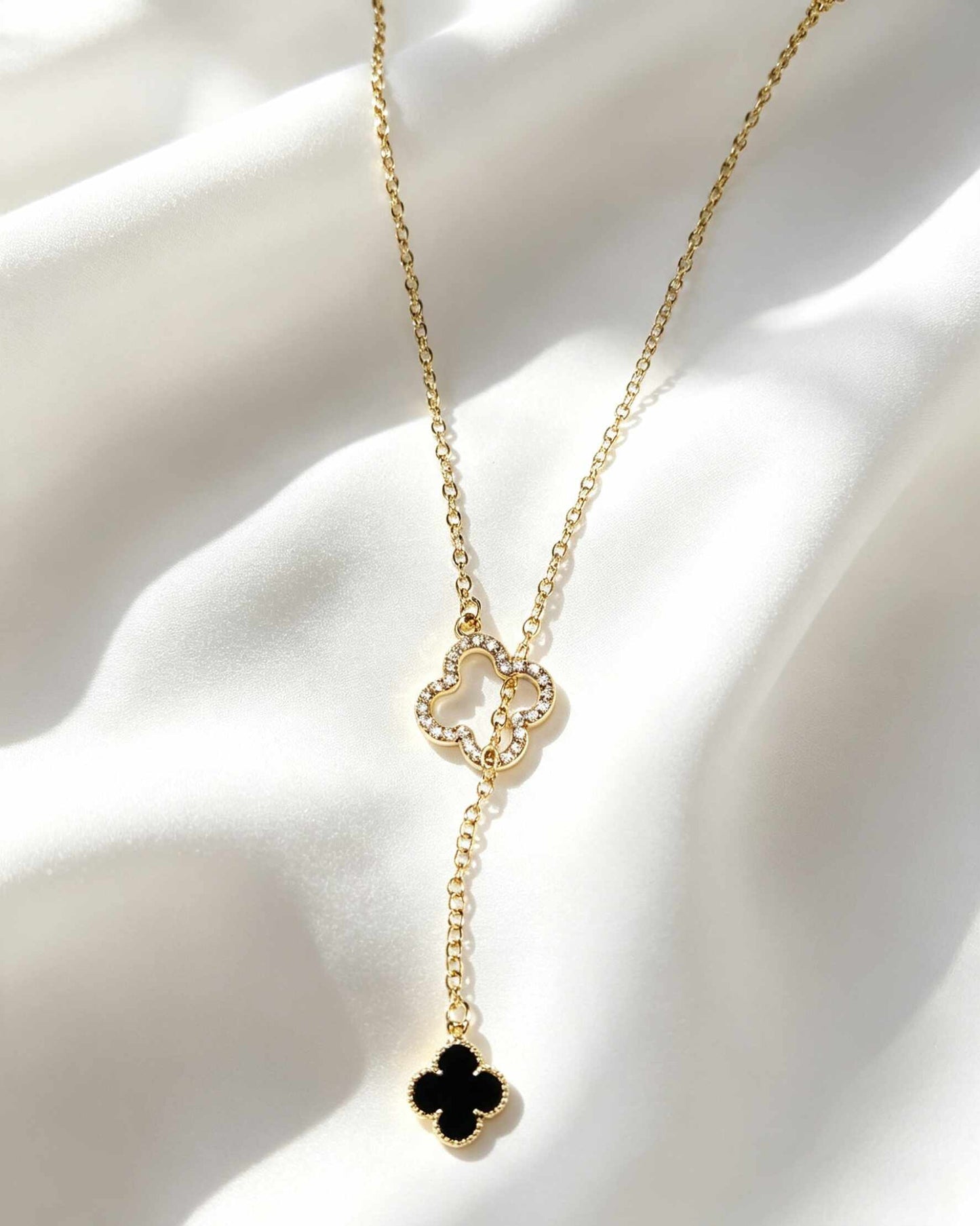 Collar estilo corbata con colgantes de trébol de cuatro hojas negro y circonias.