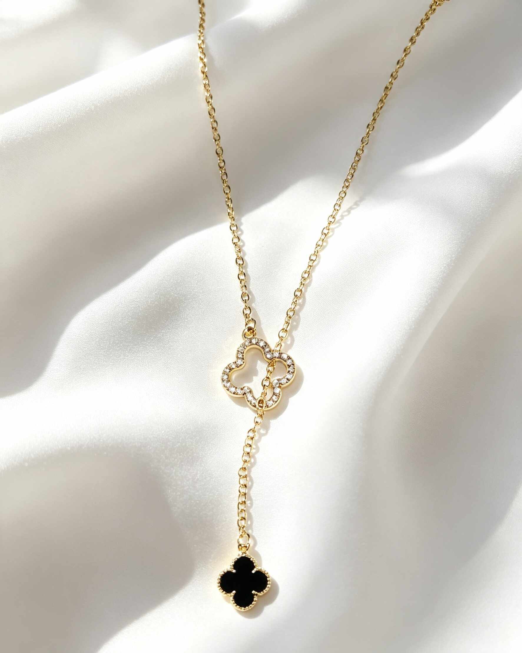 Collar estilo corbata con colgantes de trébol de cuatro hojas negro y circonias.