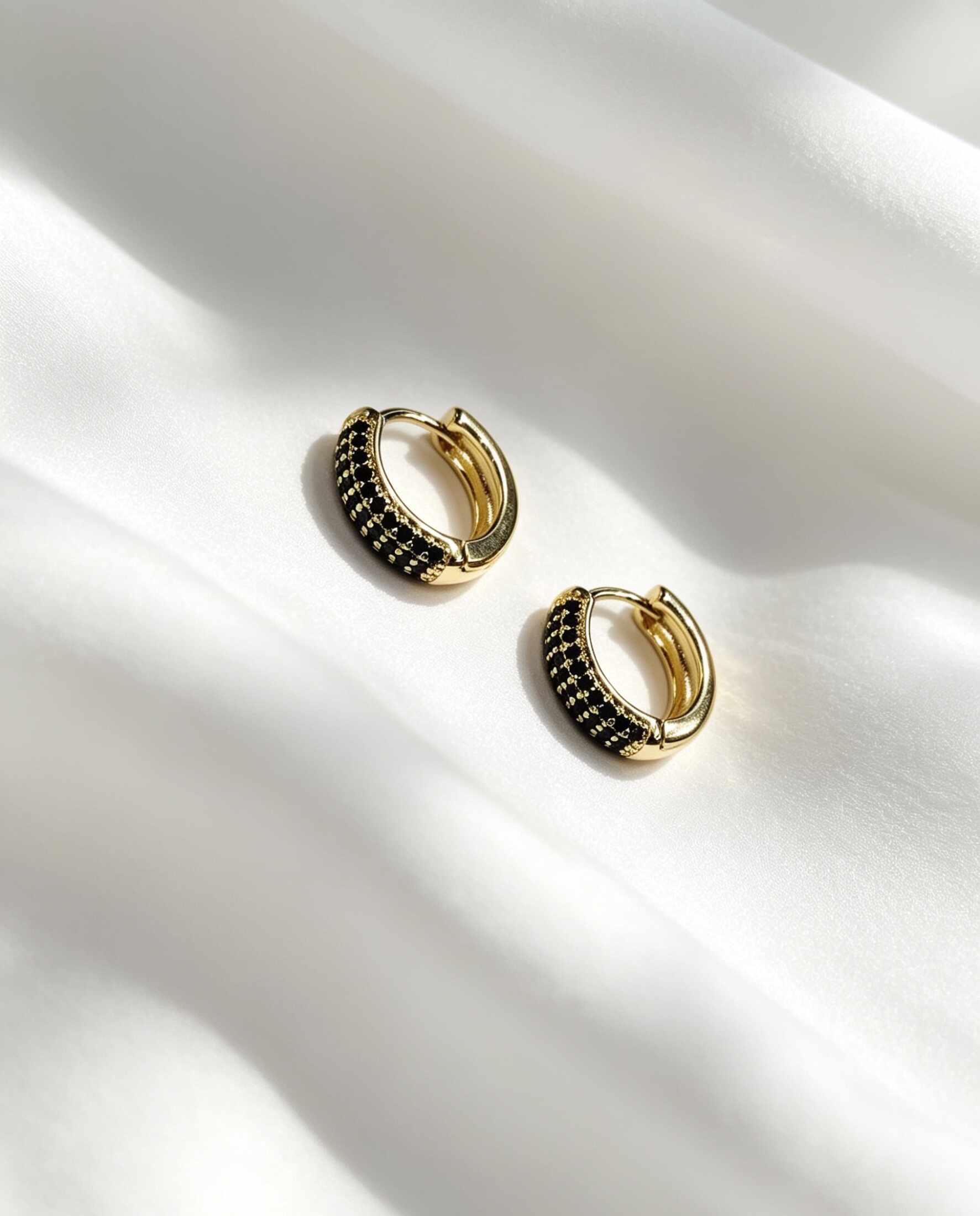 Aros redondos con circonias negras, tamaño M. Más brillo, más presencia en tu look.