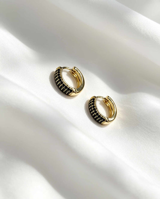 Aros redondos con circonias negras, tamaño M. Más brillo, más presencia en tu look.